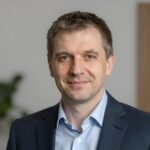 Портрет уверенного российского бизнесмена с дружелюбным взглядом на размытом нейтральном фоне студии